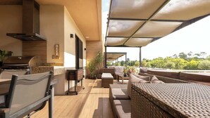 Un espace extérieur moderne, aménagé en terrasse, avec un barbecue, des sièges et une vue sur le paysage.