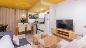 Ein modernes Wohnzimmer mit einer Couch, einem Fernseher und einem Essbereich.