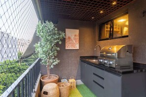 Una cuina compacta amb una graella, una planta en test i vista a l'exterior.