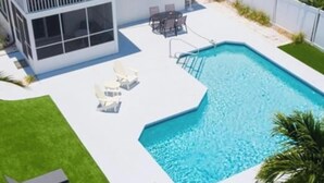 Ein modernes, zweistöckiges Haus mit Swimmingpool, einer Terrasse mit Sitzgelegenheiten und einem gepflegten Rasen.