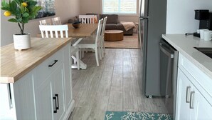 Eine moderne Küche mit weißen Schränken, einem eingebauten Kühlschrank und einem Essbereich mit einem Holztisch und Stühlen.