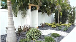 Ein angelegter Garten mit Palmen, einer Holzpergola und verschiedenen Sträuchern.