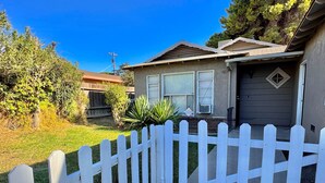 A residential house with a white picket fence, a garage, and a well-maintained lawn.