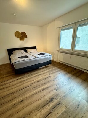 Quarto com cama, soalho de madeira, janela e radiador.