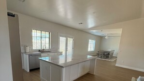 A spacious kitchen with a central island, a dining area with a table and chairs, and a built-in oven. - Newly Remodeled Chandler Gem — Stylish 3 Bed, 2 Bath Home Awaits! (Chandler)