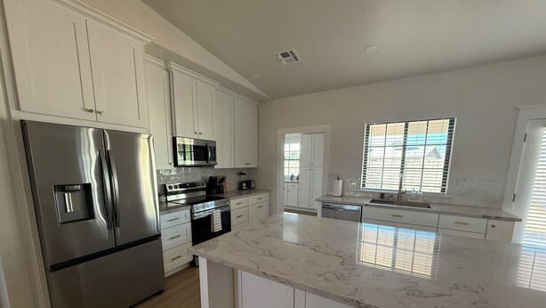 A modern kitchen with white cabinets, stainless steel appliances, and a marble countertop. - Newly Remodeled Chandler Gem — Stylish 3 Bed, 2 Bath Home Awaits! (Chandler)
