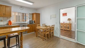 A kitchen with wooden cabinets, a dining table, and a microwave. - Vacation Villa 'Montaña' with Wi-Fi and Air Conditioning (Balcon de Telde)