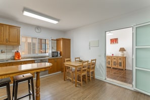 Una cocina con armarios de madera, una mesa de comedor y un microondas.