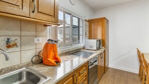 A kitchen with wooden cabinets, a stainless steel sink, a microwave, and a window with a view. - Vacation Villa 'Montaña' with Wi-Fi and Air Conditioning (Balcon de Telde)