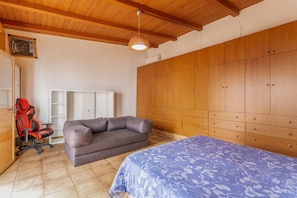 Ein Schlafzimmer mit einem Bett, einem Schlafsofa, einem Sessel und einem Kleiderschrank.