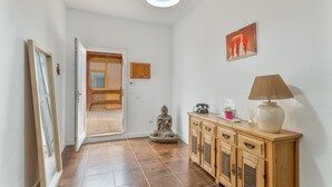 A hallway with a wooden cabinet, a statue, and a door leading to a room. - Vacation Villa 'Montaña' with Wi-Fi and Air Conditioning (Balcon de Telde)