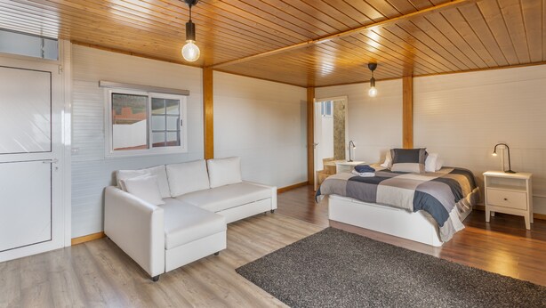 A bedroom with a bed, a white sofa, a bedside table, and a wooden ceiling. - Vacation Villa 'Montaña' with Wi-Fi and Air Conditioning (Balcon de Telde)