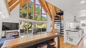 A modern kitchen with a central island, wooden beams, and large windows. - Riverfront Escape in North Alexander Vly, 3BR/2BA, hot tub, bbq, bocce ball (Cloverdale)