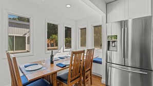 A dining area with a wooden table, blue cushioned chairs, and a stainless steel refrigerator. - Riverfront Escape in North Alexander Vly, 3BR/2BA, hot tub, bbq, bocce ball (Cloverdale)