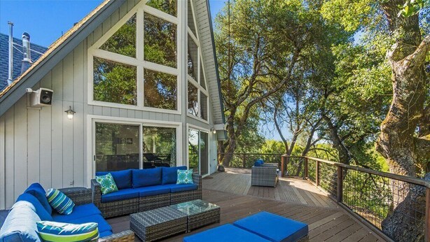 A deck with wicker furniture and cushions, overlooking a forested area. - Riverfront Escape in North Alexander Vly, 3BR/2BA, hot tub, bbq, bocce ball (Cloverdale)