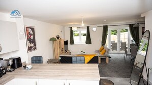 Una cocina moderna con armarios blancos, encimera de madera y zona de comedor con mesa y sillas.
