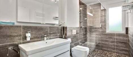 Deluxe appartement | Badkamer | Een douche, een haardroger, handdoeken, toiletpapier