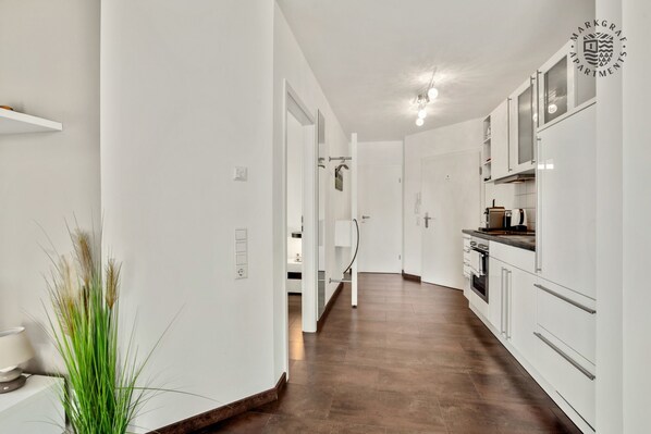 A modern kitchen with white cabinets and a built-in oven. - Markgraf Apartments (Bad Bellingen)