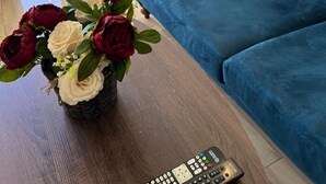 Un salon moderne avec un canapé bleu, une télécommande et un vase de fleurs.