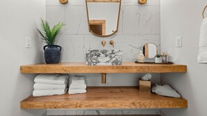 A bathroom with a wooden vanity, marble sink, and a mirror with a wooden frame. - Sommer House Inn-The Aloha Room (Newton County)