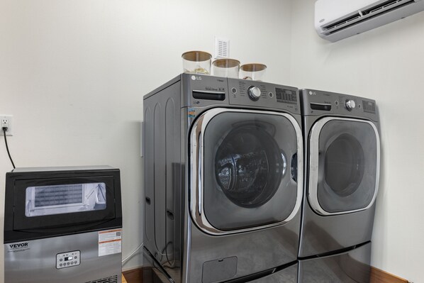 A laundry area with two front-loading LG washers, a VEVOR refrigerator, and an air conditioning unit on the wall. - Sommer House Inn-The Aloha Room (Newton County)