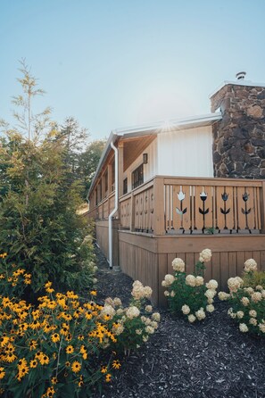 A two-story house with a stone facade and a wooden deck. - Sommer House Inn-The Aloha Room (Newton County)