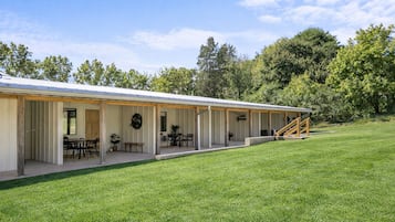 A single-story building with an open patio area, outdoor seating, and a staircase leading to an upper level.