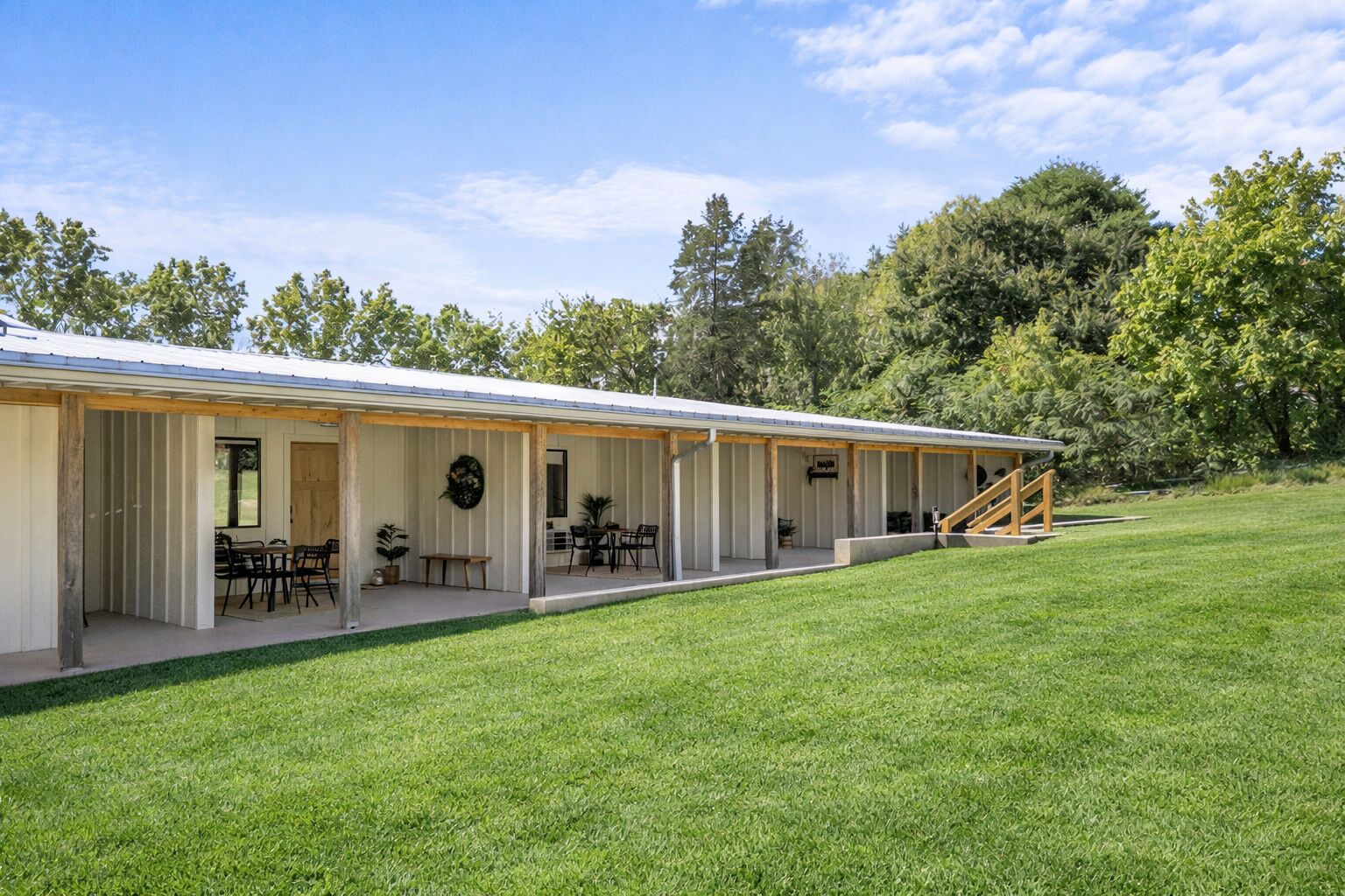 A single-story building with an open patio area, outdoor seating, and a staircase leading to an upper level.