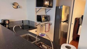 Kompakti keittiö, jossa on mikroaaltouuni, leivänpaahdin ja jääkaappi.