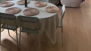 Un saló modern amb zona de menjador, televisió plana penjada a la paret i una finestra gran amb cortines.