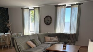Un saló modern amb un sofà modular, una taula baixa de fusta i una zona de menjador amb taula i cadires.