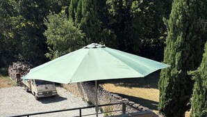 Un balcó amb barana metàl·lica, una taula i un parasol.
