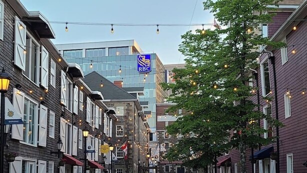 A street lined with traditional buildings, a modern glass building, and a RBC sign. - Iconic Luxurious Downtown Building History Galore (Halifax)