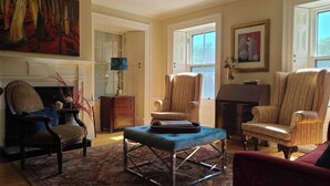 A spacious living room with a fireplace, two armchairs, a sofa, and a patterned rug. - Iconic Luxurious Downtown Building History Galore (Halifax)