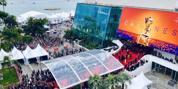 A large outdoor event with a crowd, tents, and a prominent building with a large screen displaying text. - Living in the Heart of Cannes (Cannes)