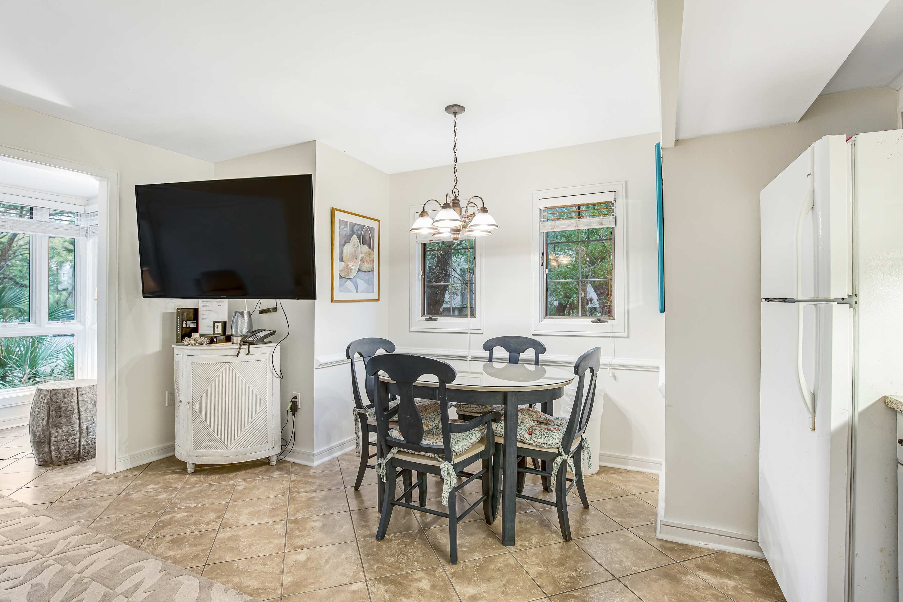 A kitchen with a dining table, chairs, a TV, and a refrigerator.