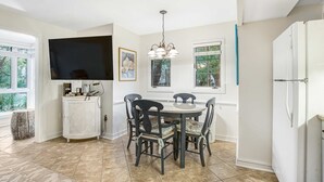 A kitchen with a dining table, chairs, a TV, and a refrigerator. - Charming condo with private beach access, on-site golf, high-speed WiFi & AC (Kiawah Island)