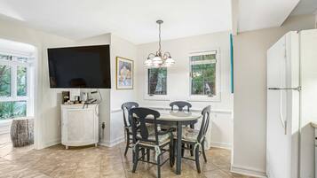 A kitchen with a dining table, chairs, a TV, and a refrigerator.