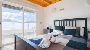 A bedroom with a bed, a nightstand, a chair, and a view of the sky. - Vacation Villa 'Adrián' with Mountain View, Wi-Fi and Air Conditioning (Las Palmas)