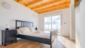 A bedroom with a wooden ceiling, a bed with a dark frame, a nightstand, and a large window. - Vacation Villa 'Adrián' with Mountain View, Wi-Fi and Air Conditioning (Las Palmas)