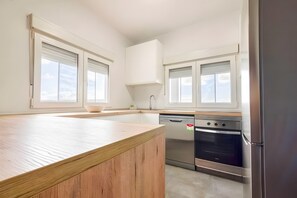 Une cuisine dotée d’un plan de travail en bois, de meubles blancs, d’un lave-vaisselle, d’un four et d’un réfrigérateur.