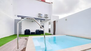 A swimming pool with a metal ladder, a door, and a small seating area with chairs. - Vacation Villa 'Adrián' with Mountain View, Wi-Fi and Air Conditioning (Las Palmas)