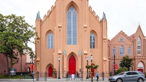 Eine Kirche mit einem großen Mittelokno, einer roten Tür und einem Glockenturm.