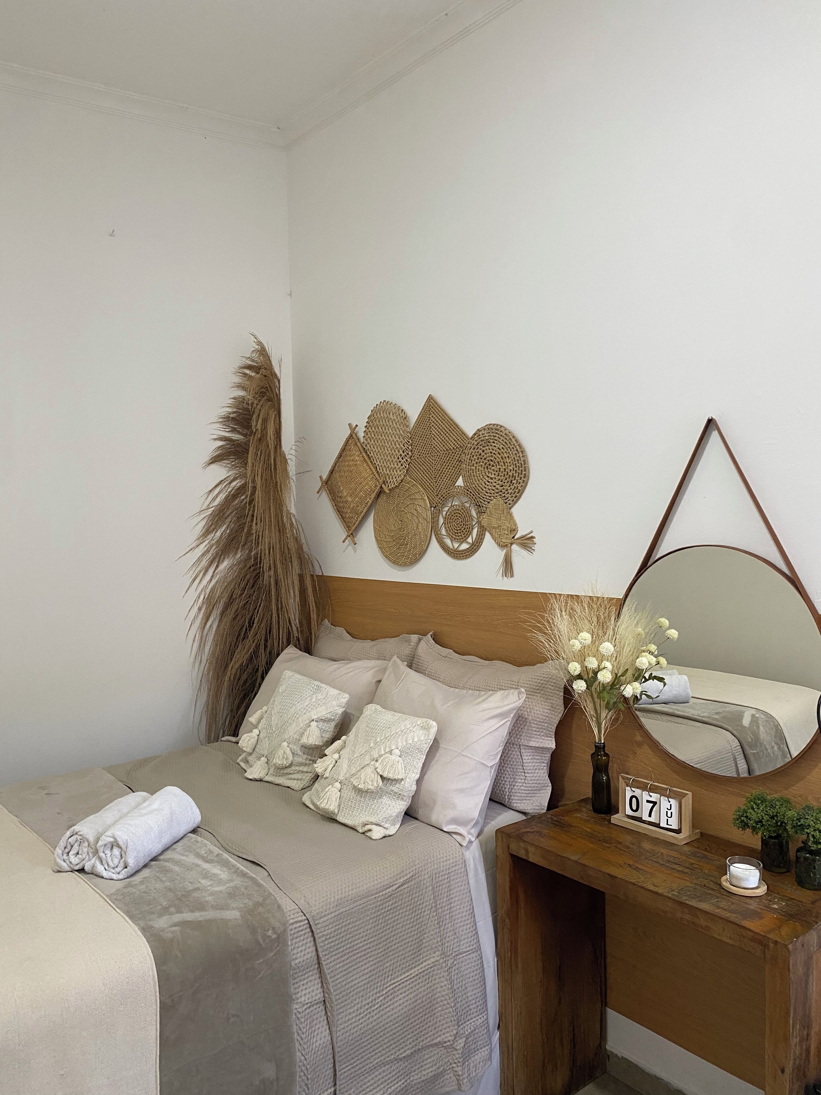 A bedroom with a bed, a nightstand, a mirror, and wall decorations.