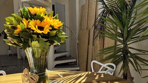 A table with a white mug, a plate of food, and a vase of flowers. - Hostel Amor por SP  (São Paulo)