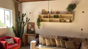 A living room with a red armchair, a beige sofa, a wooden coffee table, and a cactus plant. - Hostel Amor por SP  (São Paulo)