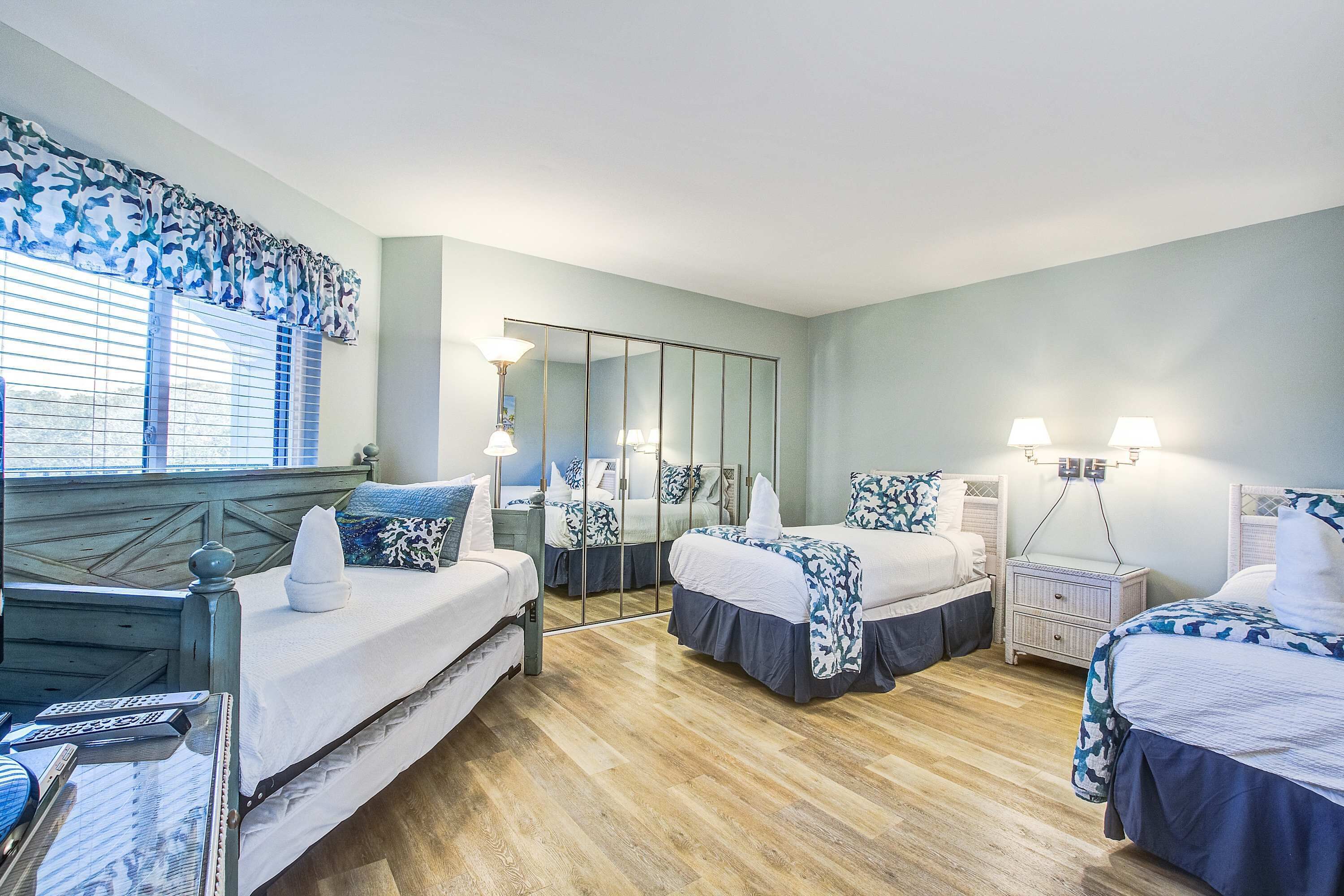 Ein Hotelzimmer mit zwei Betten, einem großen Spiegel, Nachttischlampen und Holzboden.