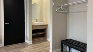 A modern bathroom with a black door, a white sink, and a mirror. - Hôtel St-Michel (Saint-Michel-des-Saints)