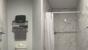 A modern bathroom with a toilet, towel rack, and shower area. - Hôtel St-Michel (Saint-Michel-des-Saints)