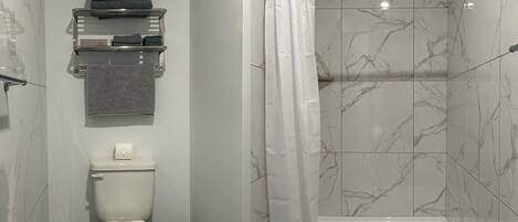 Un baño moderno con inodoro, toallero y zona de ducha.